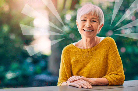 A mature woman in a bright yellow jumper smiling.