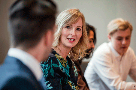 A woman is at a table of professionals.