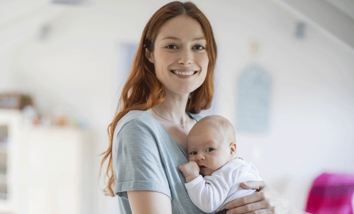 A young woman holding a new baby in her nursery