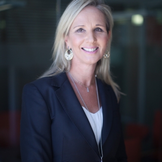 Photograph of Jane Burns smiling wearing a dark blue suit jacket and white shirt 